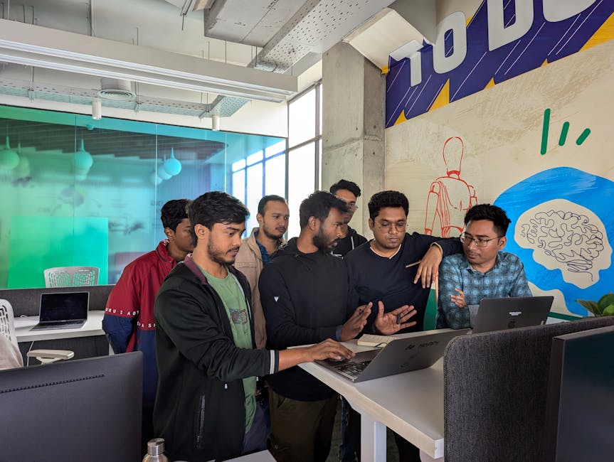 Young professionals collaborate around a laptop in a vibrant, modern office environment.