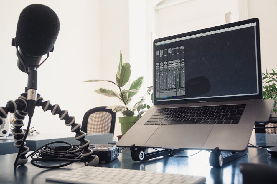 A detailed studio setup featuring a laptop and microphone on a desk for audio production.
